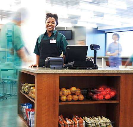 A smiling cashier in a hospital cafe.
